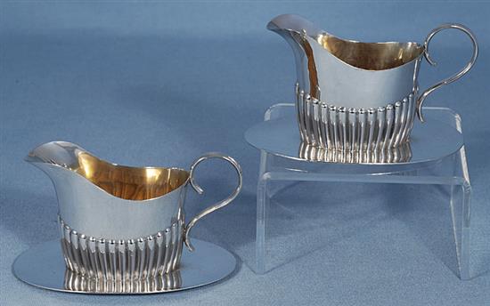 A pair of Edwardian demi fluted silver cream jugs on integral stands, length 115mm, weight 6.5oz/205grms.